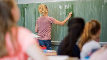 Eine Lehrerin schreibt an eine Schultafel. 