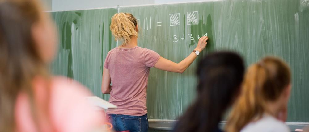 Eine Lehrerin schreibt an eine Schultafel. 