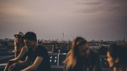 Friends talking while sitting on terrace during rooftop party in city at dusk