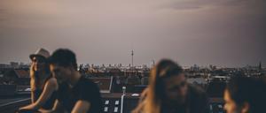 Friends talking while sitting on terrace during rooftop party in city at dusk