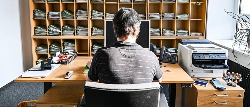 Ein Verwaltungsmitarbeiter sitzt in einem Büro am Schreibtisch.