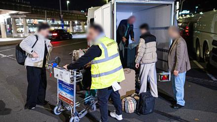 Langenhagen: Menschen aus Afghanistan, die zuvor mit einem Flugzeug auf dem Flughafen Hannover-Langenhagen gelandet sind, stehen vor dem Flughafen und verladen ihr Gepäck.
