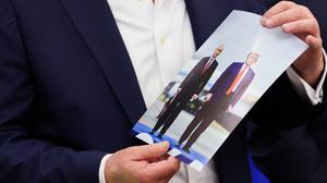 Donald Trump hält ein Foto von sich mit Wladimir Putin in der Hand
