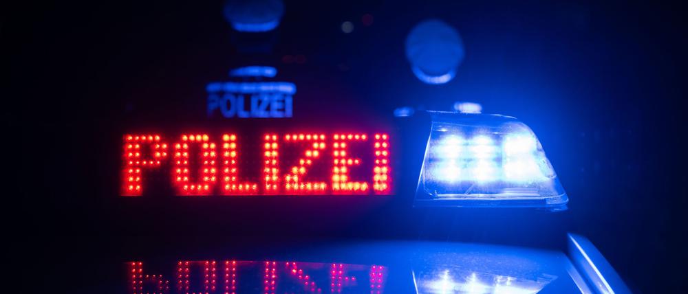 Zwei Polizisten stehen vor einem Polizeifahrzeug (Symbolbild).
