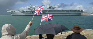 Menschen in Portsmouth stehen am Ufer und winken dem Flugzeugträger der britischen Royal Navy HMS Queen Elizabeth zu.
