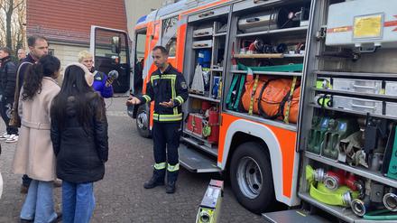 Feuerwehrmann Marcel stellt an der Alfred-Nobel-Schule das Feuerwehrfahrzeug vor.