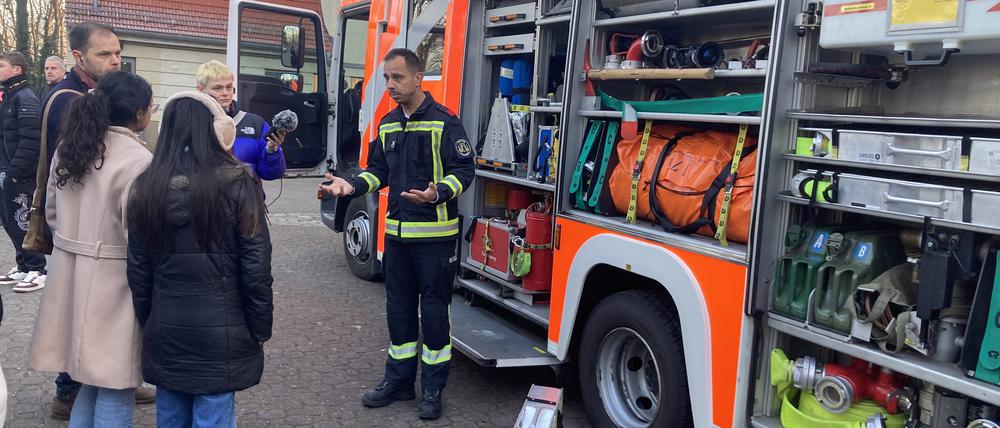 Feuerwehrmann Marcel stellt an der Alfred-Nobel-Schule das Feuerwehrfahrzeug vor.