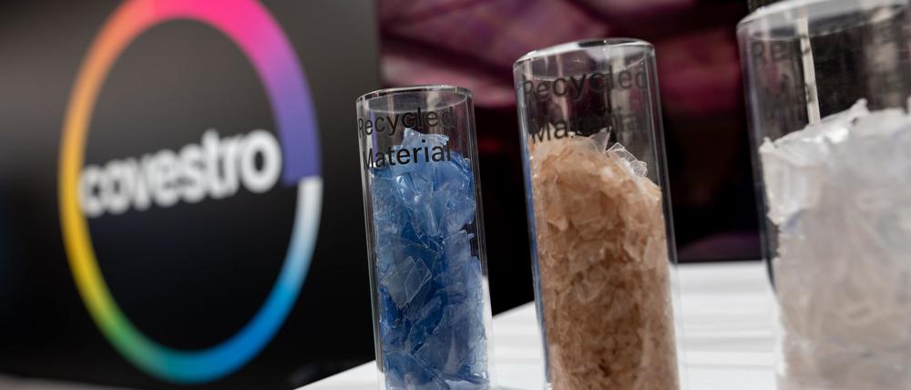 Eine deutsche Firma wird arabisch: Das Logo des Spezialchemie-Konzerns in einem Firmen-Showroom, davor Gläser mit Covestro-Materialien. 