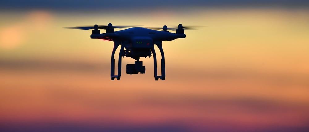 Eine Drohne fliegt bei Sonnenuntergang über eine Wiese. An den deutschen Flughäfen sind im ersten Quartal dieses Jahres mehr illegale Drohnen gesichtet worden als ein Jahr zuvor.