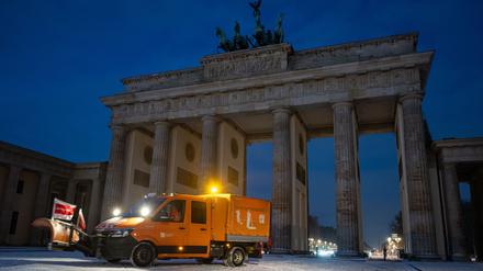 Ein Räumfahrzeug fährt nach dem ersten Schneefall vor dem Brandenburger Tor.
