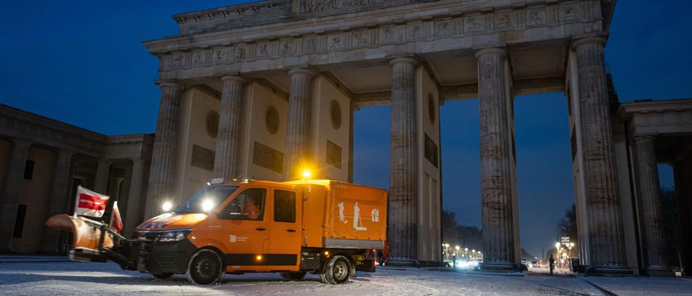 Ein Räumfahrzeug fährt nach dem ersten Schneefall vor dem Brandenburger Tor.