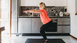 Eine Frau macht Kniebeugen in der Küche.