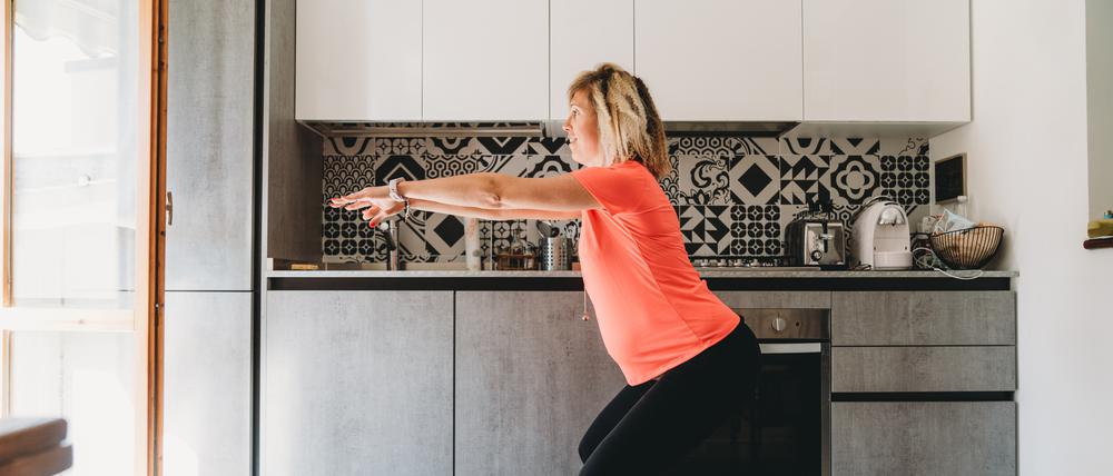 Eine Frau macht Kniebeugen in der Küche.