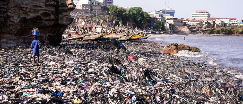 Ein Sandstrand, dessen Sand gar nicht mehr zu sehen ist: Massen an Klamotten vermüllen diesen Küstenabschnitt von Accra.