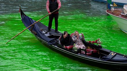 Touristen bei einer Gondelfahrt auf dem Canal Grande in Venedig am 22. November 2025, wo das Kanalwasser von Klimaaktivisten grün gefärbt wurde.