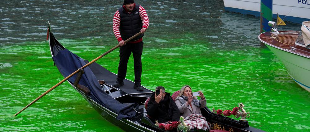 Touristen bei einer Gondelfahrt auf dem Canal Grande in Venedig am 22. November 2025, wo das Kanalwasser von Klimaaktivisten grün gefärbt wurde.