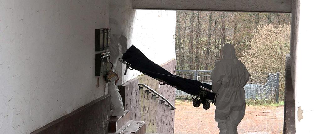 Beamte der Spurensicherung bringen eine Trage in ein Wohnhaus.