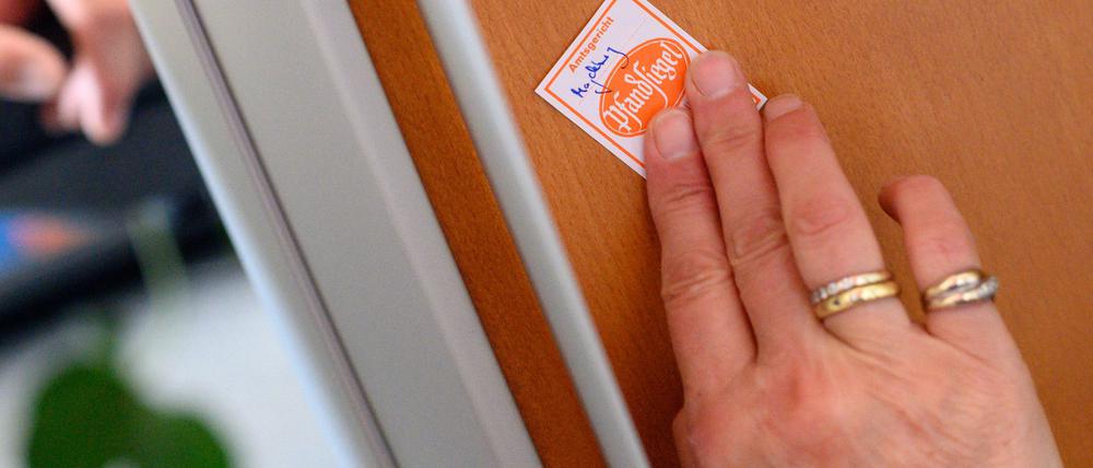 Eine Gerichtsvollzieherin klebt ein Pfandsiegel auf ein technisches Gerät. (Symbolbild) 