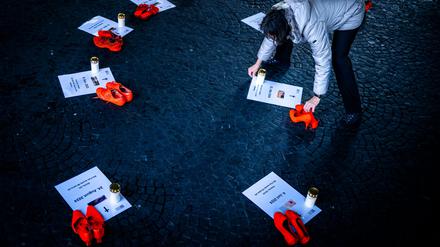 25.11.2025, Schweiz, Zürich: Eine Freiwillige platziert Kerzen neben orangen Schuhen und Plakaten für Opfer von Femiziden als Teil einer Installation "Gedenken an getoetete Frauen durch Femizide 2024 - 2025" bei der Wasserkirche, anlässlich der Kampagne 16 Tage gegen Gewalt an Frauen. Der "Internationale Tag gegen Gewalt an Frauen", auch als "Orange Day" bekannt, wird seit mehr als drei Jahrzehnten jährlich am 25. November begangen. Weltweit wird an diesem Tag mit orange beleuchteten Gebäuden, Demonstrationen und weiteren Veranstaltungen auf die anhaltende Gewalt gegen Frauen und Mädchen hingewiesen. Foto: Michael Buholzer/KEYSTONE/dpa +++ dpa-Bildfunk +++