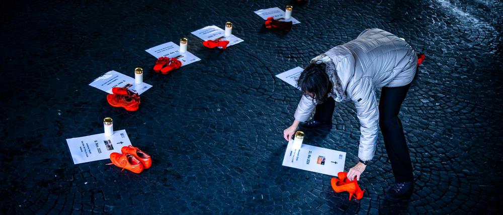 25.11.2025, Schweiz, Zürich: Eine Freiwillige platziert Kerzen neben orangen Schuhen und Plakaten für Opfer von Femiziden als Teil einer Installation "Gedenken an getoetete Frauen durch Femizide 2024 - 2025" bei der Wasserkirche, anlässlich der Kampagne 16 Tage gegen Gewalt an Frauen. Der "Internationale Tag gegen Gewalt an Frauen", auch als "Orange Day" bekannt, wird seit mehr als drei Jahrzehnten jährlich am 25. November begangen. Weltweit wird an diesem Tag mit orange beleuchteten Gebäuden, Demonstrationen und weiteren Veranstaltungen auf die anhaltende Gewalt gegen Frauen und Mädchen hingewiesen. Foto: Michael Buholzer/KEYSTONE/dpa +++ dpa-Bildfunk +++