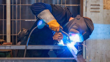 Ein Arbeiter in der Metallindustrie schweißt. 