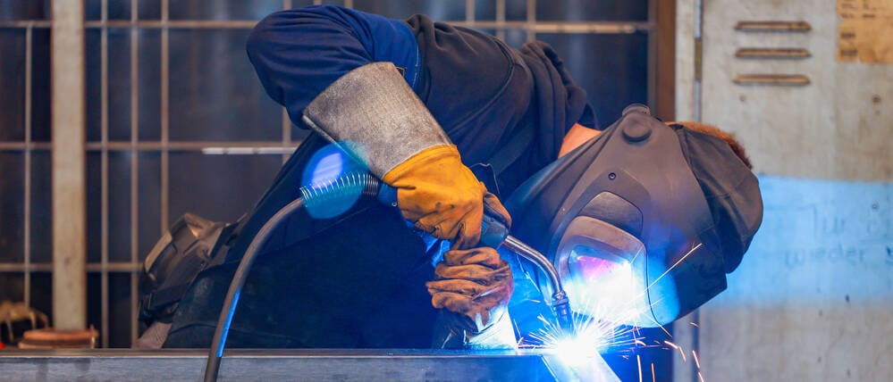 Ein Arbeiter in der Metallindustrie schweißt. 