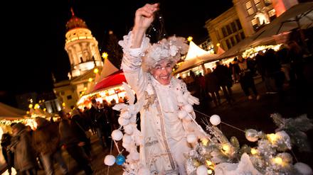 Ein weihnachtlich verkleideter Besucher verteilt am 23.11.2015 auf dem Weihnachtsmarkt am Gendarmenmarkt in Berlin "künstlichen Schnee". Foto: Jörg Carstensen/dpa +++(c) dpa - Bildfunk+++ | Verwendung weltweit