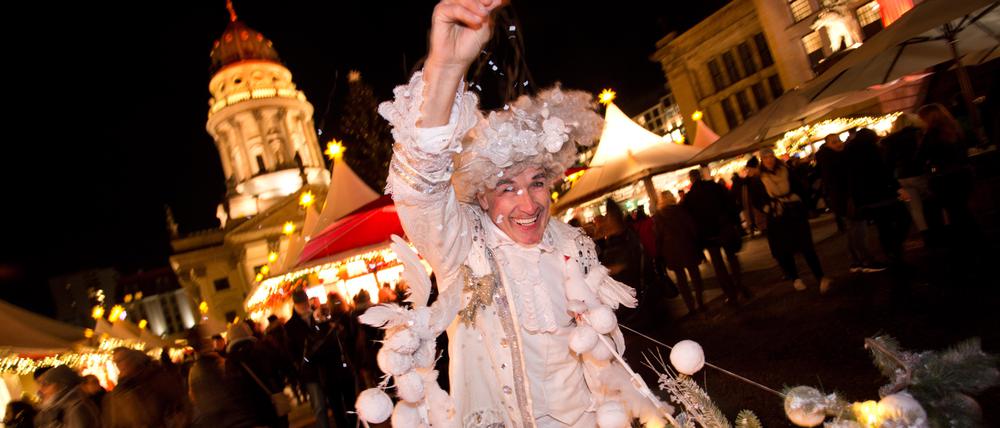 Ein weihnachtlich verkleideter Besucher verteilt am 23.11.2015 auf dem Weihnachtsmarkt am Gendarmenmarkt in Berlin "künstlichen Schnee". Foto: Jörg Carstensen/dpa +++(c) dpa - Bildfunk+++ | Verwendung weltweit