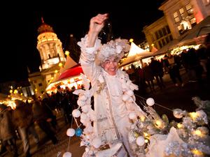 Ein weihnachtlich verkleideter Besucher verteilt am 23.11.2015 auf dem Weihnachtsmarkt am Gendarmenmarkt in Berlin "künstlichen Schnee". Foto: Jörg Carstensen/dpa +++(c) dpa - Bildfunk+++ | Verwendung weltweit