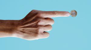 Der Zeigefinger einer männlichen Hand zeigt auf eine Ein-Euro-Münze.