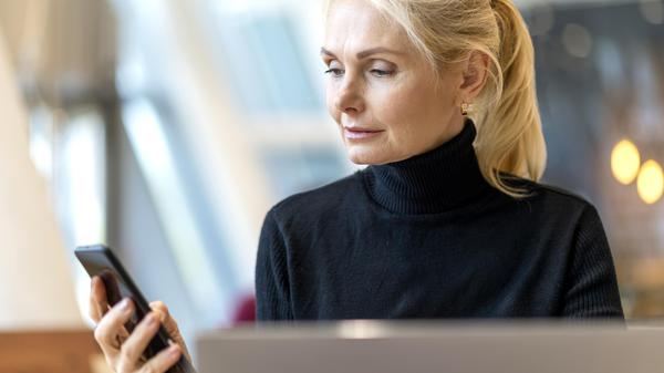Eine Frau blickt prüfend auf ihr Smartphone.  