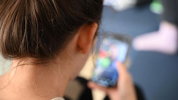 Symbolbild: Eine Person öffnet auf ihrem Smartphone einen Ordner mit Apps verschiedener sozialer Medien. 