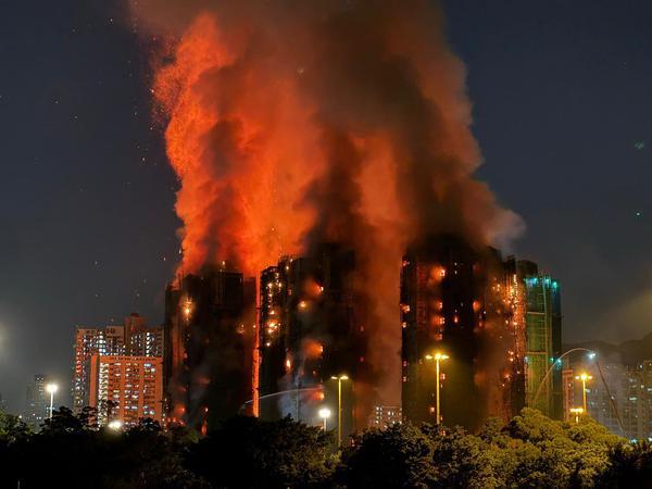 TOPSHOT - Thick smoke and flames rise as a major fire engulfs several apartment blocks at the Wang Fuk Court residential estate in Hong Kong's Tai Po district on November 26, 2025. At least four people were killed when a fire engulfed several high-rise blocks in a Hong Kong residential estate on November 26, the government said, with media reporting that some residents were trapped inside. (Photo by Yan ZHAO / AFP)