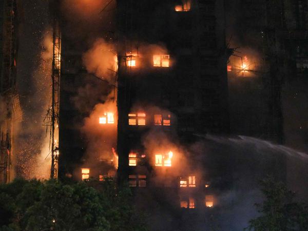Flames rise as a major fire engulfs several apartment blocks at the Wang Fuk Court residential estate in Hong Kong's Tai Po district on November 26, 2025. At least four people were killed when a fire engulfed several high-rise blocks in a Hong Kong residential estate on November 26, the government said, with media reporting that some residents were trapped inside. (Photo by Tommy WANG / AFP)