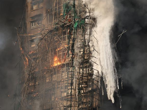 Smoke rises while flames burn bamboo scaffolding on a building at Wang Fuk Court housing estate, in Tai Po, Hong Kong, China, November 26, 2025. REUTERS/Tyrone Siu