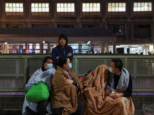 Evacuees wrapped in blankets rest on a nearby platform after a major fire at Wang Fuk Court housing estate, in Tai Po, Hong Kong, China, November 26, 2025. REUTERS/Tyrone Siu