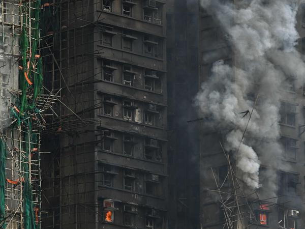 Apartments still burn as a major fire swept through several apartment blocks at the Wang Fuk Court residential estate in Hong Kong's Tai Po district on November 27, 2025. Firefighters were still dousing a devastating fire on November 27 which ripped through a Hong Kong high-rise complex, killing at least 44 people and leaving hundreds missing according to authorities. (Photo by Peter PARKS / AFP)