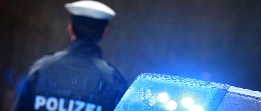 Ein Polizist steht vor einem Streifenwagen (Symbolbild).