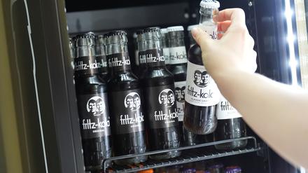 Eine Mitarbeiterin greift nach einer Flasche Fritz-Kola in einem Kühlschrank in der Firmenzentrale der Fritz-Kola GmbH (Symbolbild).