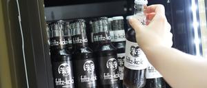 Eine Mitarbeiterin greift nach einer Flasche Fritz-Kola in einem Kühlschrank in der Firmenzentrale der Fritz-Kola GmbH (Symbolbild).