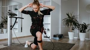 Eine Frau macht EMS-Training zu Hause. Mit Übungen kombiniert, ist es noch effektiver.