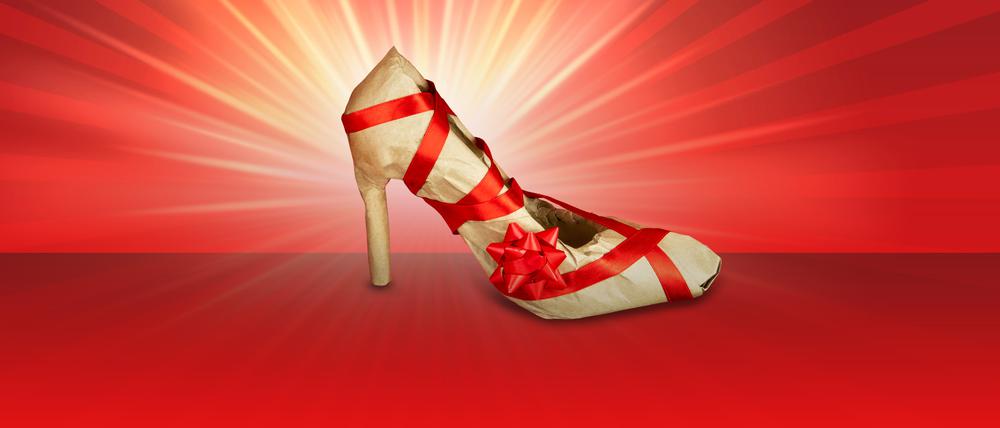 Ein Stöckelschuh ist in Papier verpackt und mit einer roten Schleife versehen. (Symbolbild)