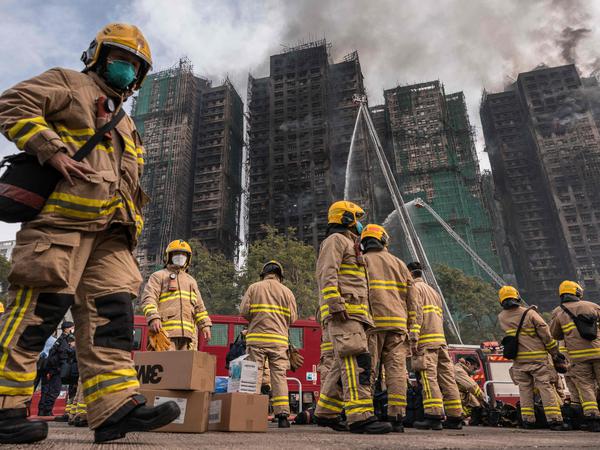 Firemen get ready after a major fire swept through several apartment blocks at the Wang Fuk Court residential estate in Hong Kong's Tai Po district on November 27, 2025. Hong Kong firefighters were scouring a still-burning apartment complex for hundreds of missing people on November 27, a day after the blaze tore through the high-rises, killing at least 44. (Photo by Dale DE LA REY / AFP)