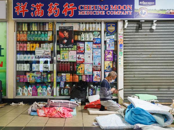 A displaced resident rests on a donated mattress at a hallway inside a shopping mall near the scene of a major fire that swept through several apartment blocks at the Wang Fuk Court residential estate in Hong Kong's Tai Po district on November 27, 2025. Hong Kong authorities said on November 28 the death toll from the city's worst fire in decades had risen to at least 94, with the blaze almost entirely extinguished and rescuers scouring torched high-rise buildings for scores of people still listed as missing. (Photo by Yan ZHAO / AFP)