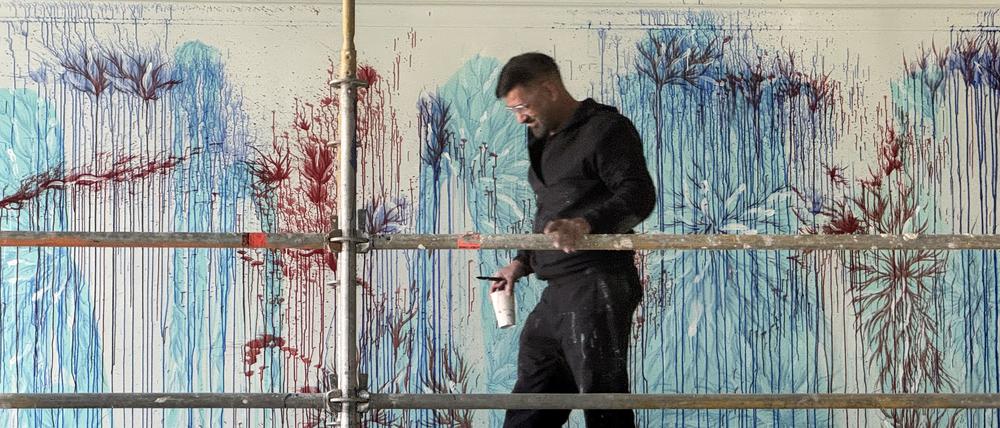 Imran Qureshi mit Pinsel Größe 14 und einem Becher mit Farbe, den er immer wieder an der Wand ausgießt. F