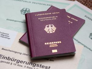 Zwei deutsche Reisepässe liegen auf Einbürgerungsurkunden der Bundesrepublik Deutschland sowie einem Einbürgerungstest.