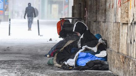 Eine Person liegt bei eisigen Temperaturen unter einer Brücke.