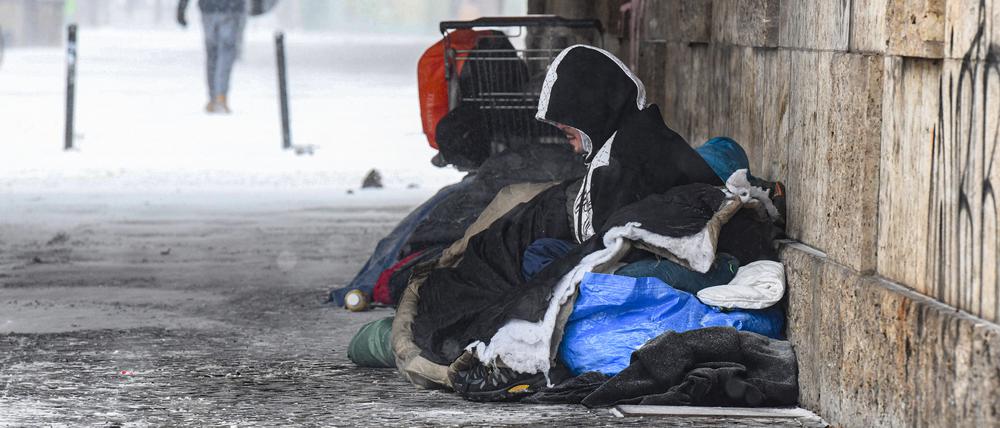 Eine Person liegt bei eisigen Temperaturen unter einer Brücke.