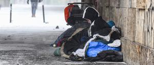 Eine Person liegt bei eisigen Temperaturen unter einer Brücke.