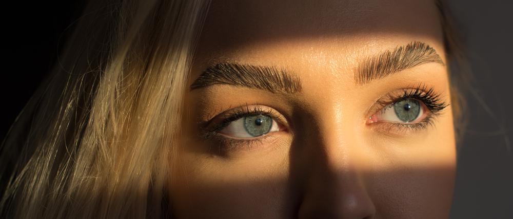 Das Gesicht einer Frau liegt im Schatten, nur die Augen im Licht.